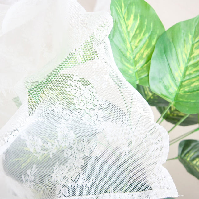 Vit spetsgardin med romantiskt blommönster