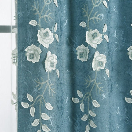 Blå gardin med vita broderade blommor