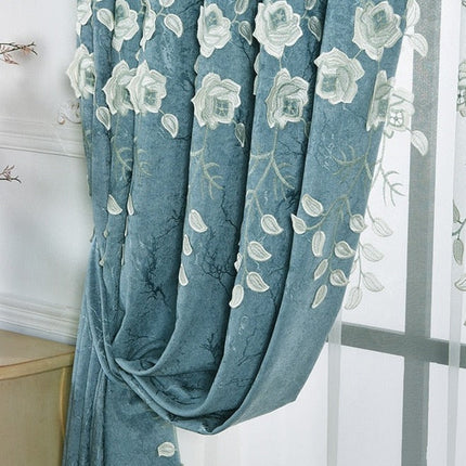 Blå gardin med vita broderade blommor