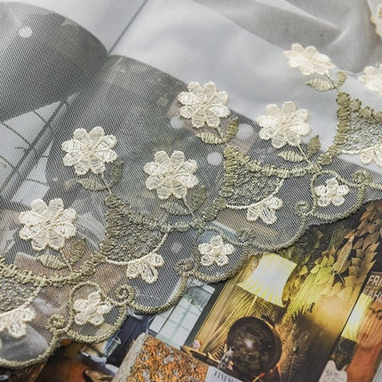 Vit tunn gardin med små blommor