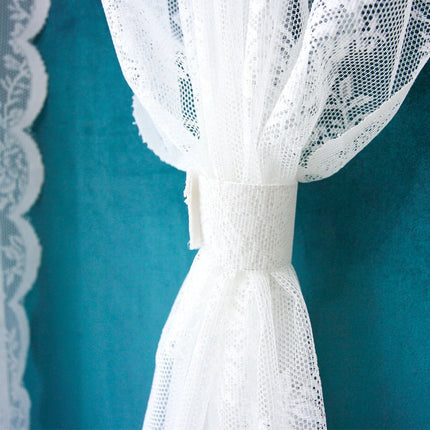 Vit spetsgardin med romantiskt blommönster