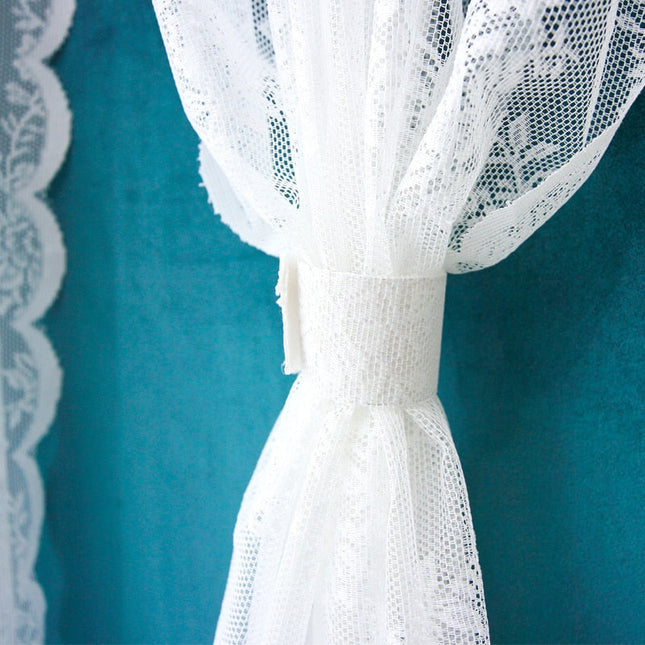 Vit spetsgardin med romantiskt blommönster